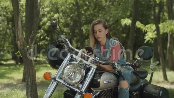 可爱的女孩在打电话靠在摩托车上视频的预览图