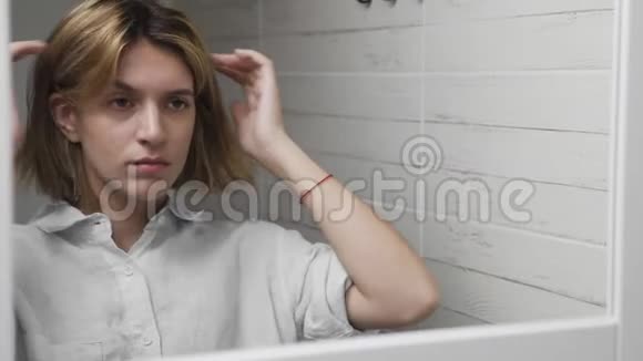 女人摸着她的脸照着镜子视频的预览图