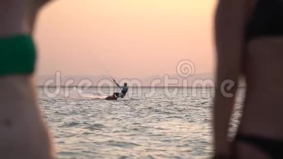 风筝冲浪者在海上滑行模糊的年轻女子在前景视频的预览图