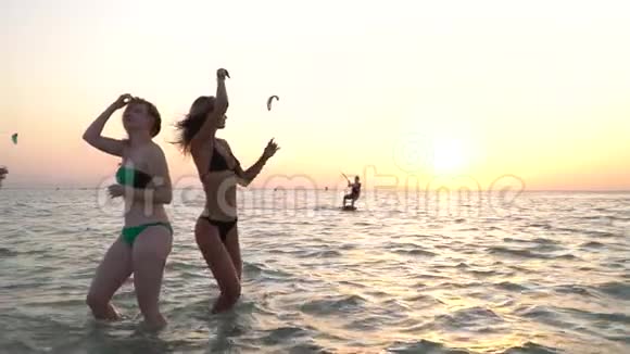 埃及的海滩派对上两个女人在海里跳舞风筝冲浪者在滑翔视频的预览图