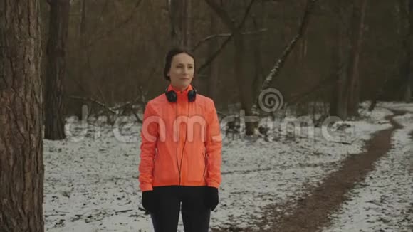女孩戴上耳机冬季公园户外跑步训练前身材优美的女子戴上耳机女性视频的预览图