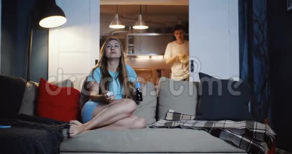 快乐的年轻欧洲休闲朋友在家里沙发上看电影吃零食聊天慢动作视频的预览图