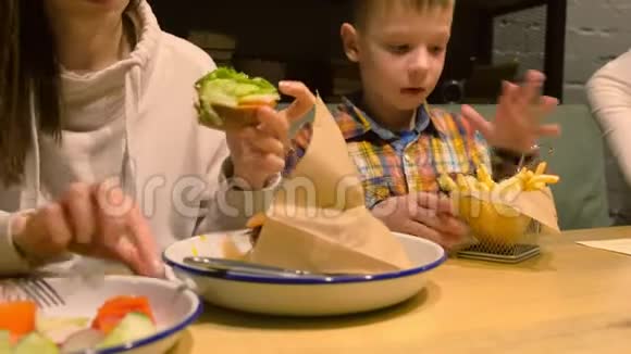 妈妈和儿子正在咖啡馆吃快餐汉堡和薯条视频的预览图