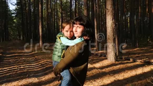 一个女人在森林或公园的背景下抱着一个小男孩母亲和儿子表现出情感视频的预览图