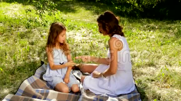 美丽的母女在公园里玩石头纸剪刀的游戏视频的预览图