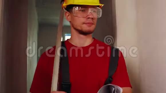 草稿公寓一个戴着黄色头盔的男工人拿着一个标尺在这个地区行走视频的预览图