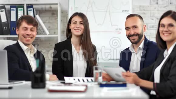 在公司会议上一群微笑的商务人士穿着西装摆姿势看镜头视频的预览图