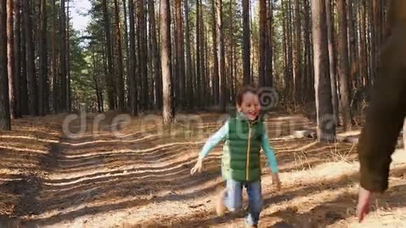 一个小男孩在森林的背景下沿着道路奔跑妈妈把孩子抱在怀里拥抱视频的预览图