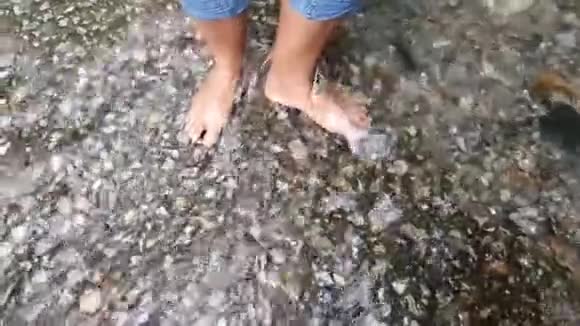 一个穿着牛仔裤的女士的脚慢慢地浸着水视频的预览图
