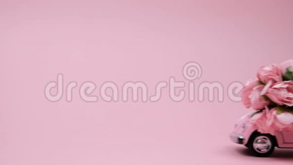 女性手推粉红色复古玩具车与花束在粉红色背景二月十四日卡情人节8视频的预览图