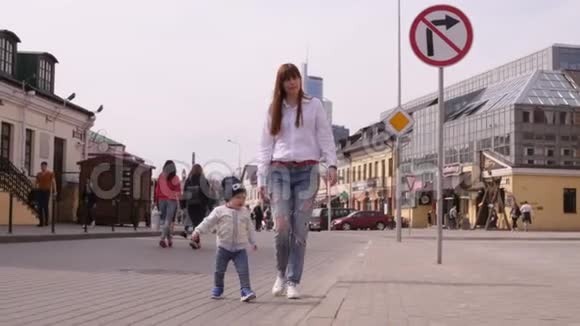 年轻的美女和她的小儿子正走在城市历史中心的步行街上视频的预览图