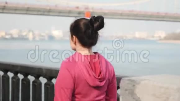 近距离观看年轻的胖乎乎的女性在城市河流上行走背景是桥减肥概念视频的预览图