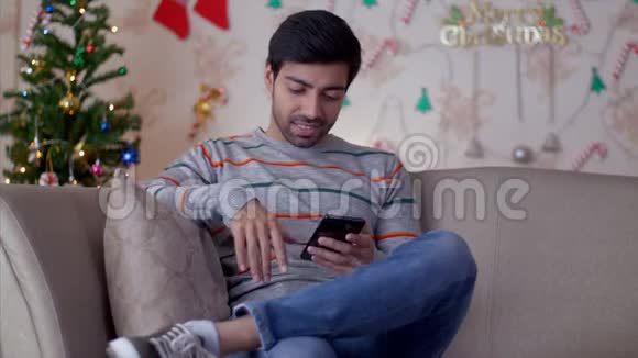 年轻人在智能手机上发短信和聊天背景是圣诞树视频的预览图