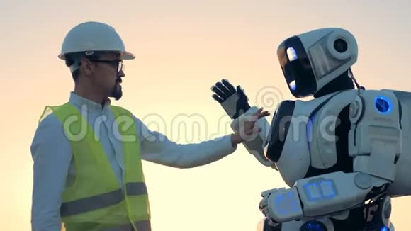 类似人类的机器人设置正在由一个硬帽的工程师调节视频的预览图