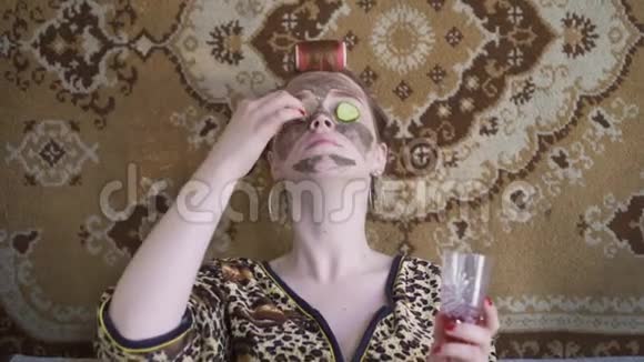 一个女孩脸上戴着面具头上戴着毛巾用黄瓜闭上眼睛复古风格视频的预览图