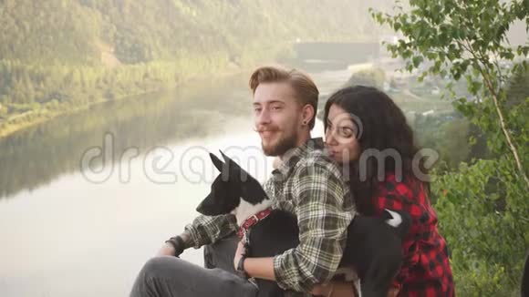 年轻的一对游客带着他们的狗在山上休息视频的预览图