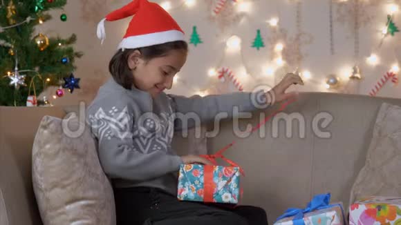坐在沙发上打开圣诞礼物的小女孩视频的预览图