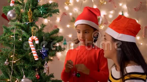 年轻的妈妈帮女儿装饰圣诞树视频的预览图