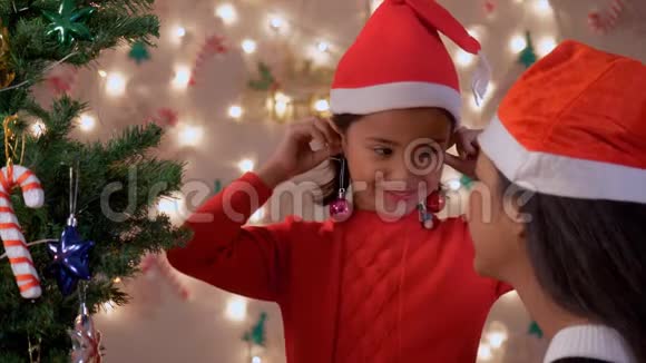 可爱的小女孩在玩用圣诞装饰球做耳环视频的预览图