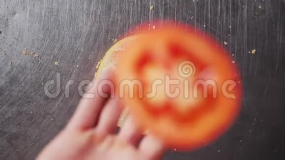 女人把番茄片扔到金属桌上的汉堡包上视频的预览图