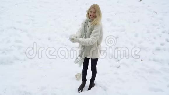 金发的年轻女人做雪球冬天与雪的游戏冬天的女人玩雪球快乐女孩带着雪球视频的预览图