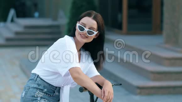 城市里一个坐在电动滑板车上的女人的肖像视频的预览图