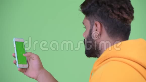 使用电话的年轻超重留胡子印度男子的近距离后视镜视频的预览图