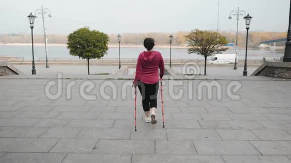 北欧式步行后面跟着一张照片照片上胖乎乎的女性在城市里用体育杆走路背景是交通和河流视频的预览图