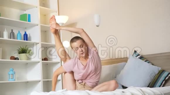 自信的运动型年轻女性在家锻炼后坐在床上做伸展运动视频的预览图