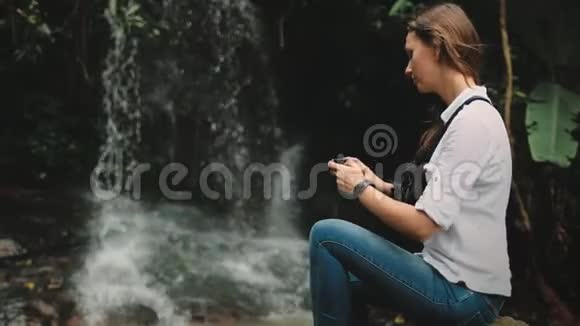 女旅行者站在雨林瀑布附近视频的预览图