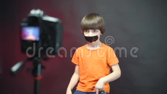 一个穿橙色衣服的男孩在镜头前用密封的嘴手势视频的预览图