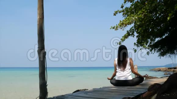 4K在暑假期间亚洲女人坐在海上的木桥上练习集中注意力视频的预览图