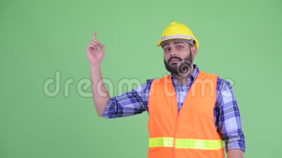 穿着年轻超重留胡子的印度建筑工人思考并指出视频的预览图