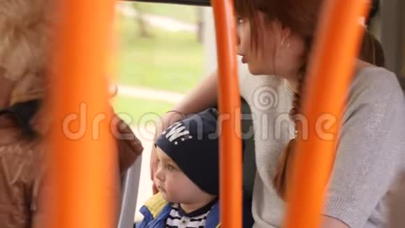 阳光明媚的日子里年轻的母亲和小儿子乘公共汽车穿过城市视频的预览图