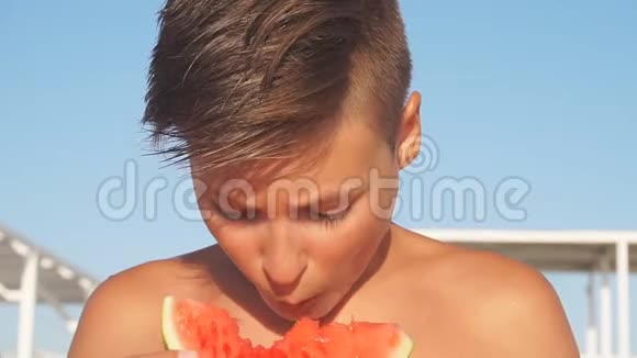 欧洲青少年在度假时在海滩上吃成熟的新鲜西瓜视频的预览图