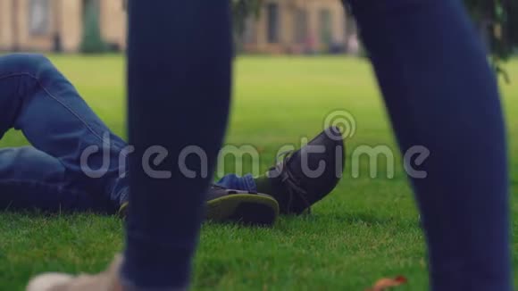 穿着牛仔裤躺在绿草地上紧贴着人的腿视频的预览图