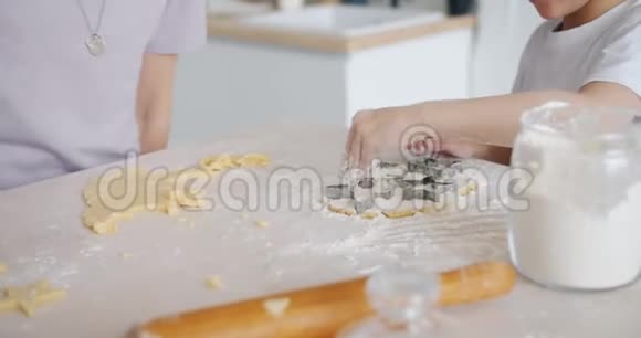 在厨房的餐桌上孩子们用面团和面粉帮妈妈做饼干视频的预览图