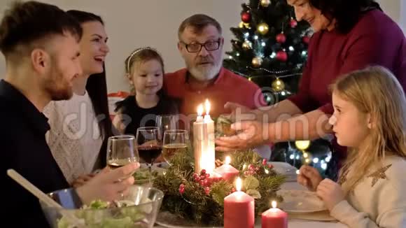 幸福的一家人一起庆祝节日坐在装饰好的圆桌旁妈妈提供晚餐客厅视频的预览图