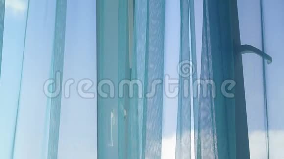 宽大的窗户上有蓝色透明的窗帘窗外的风视频的预览图