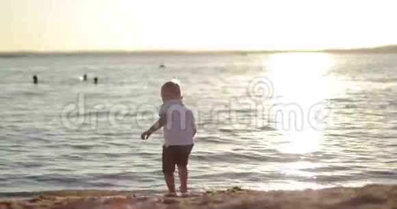 可爱的宝宝在夕阳的背景下在湖边跑来跑去视频的预览图