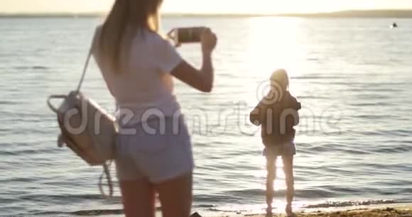 妈妈在日落的背景上给女儿拍照视频的预览图