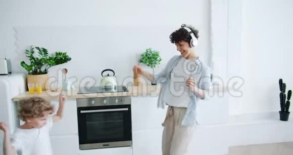 妈妈戴着耳机小儿子在厨房跳舞一起玩视频的预览图