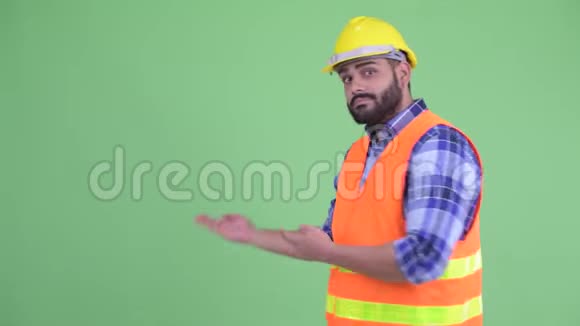 穿着年轻超重留胡子的印度男建筑工人向后展示视频的预览图