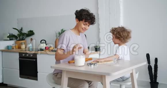 在家里和照顾孩子的母亲在餐桌旁做糕点的小孩视频的预览图