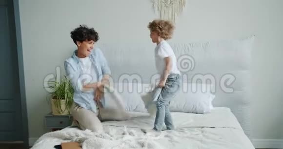 幸福的家庭母子在家里打枕头在床上大笑视频的预览图
