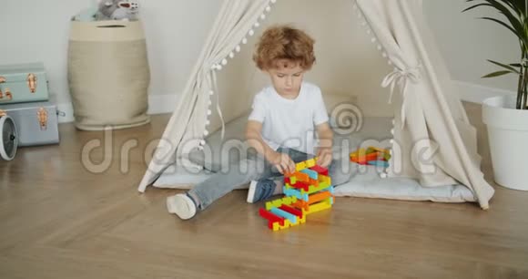 小男孩在家里坐在地板上玩玩具的慢动作视频的预览图