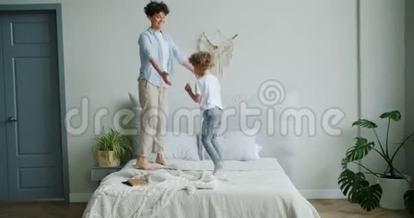 快乐的母亲和儿子一起在床上蹦蹦跳跳的慢动作视频的预览图