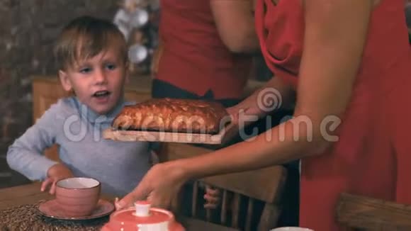 妈妈把烤好的馅饼放在桌子上儿子期待着喝茶视频的预览图