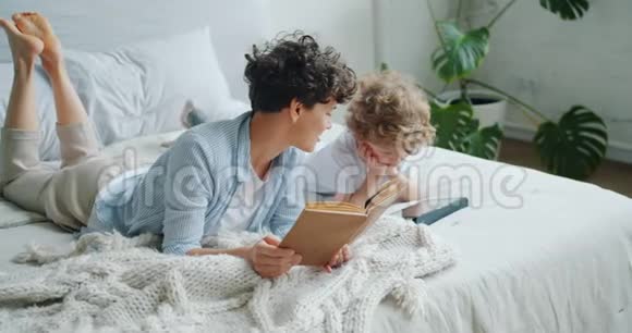 快乐的家庭妈妈和孩子在家里的床上看书和使用平板电脑视频的预览图