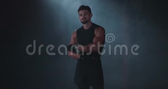 健美男子肖像站在相机前在一个带有黑色背景的体育课上摆姿势视频的预览图
